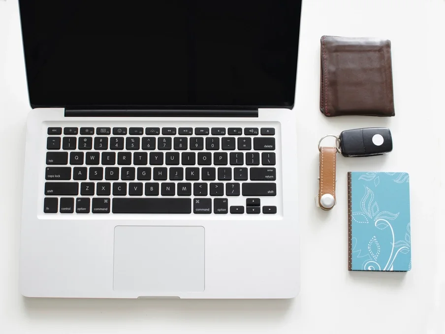 Laptop, notebook and phone laid out on a white desk